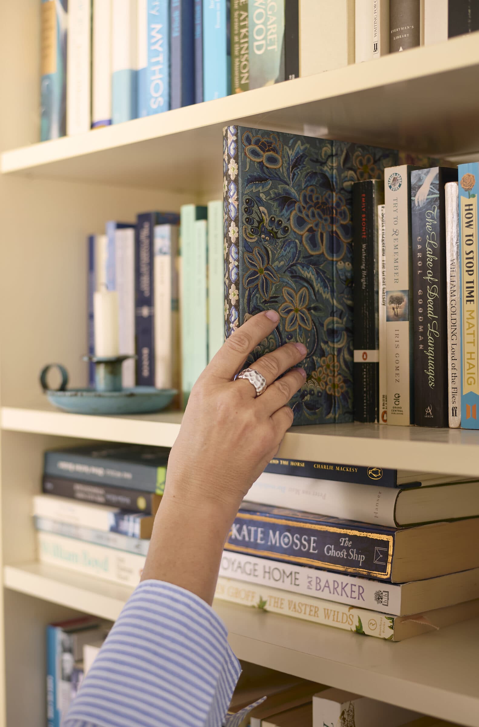 Hand greift nach einem Buch im Regal — wir sind die Geschichten, die wir uns erzählen